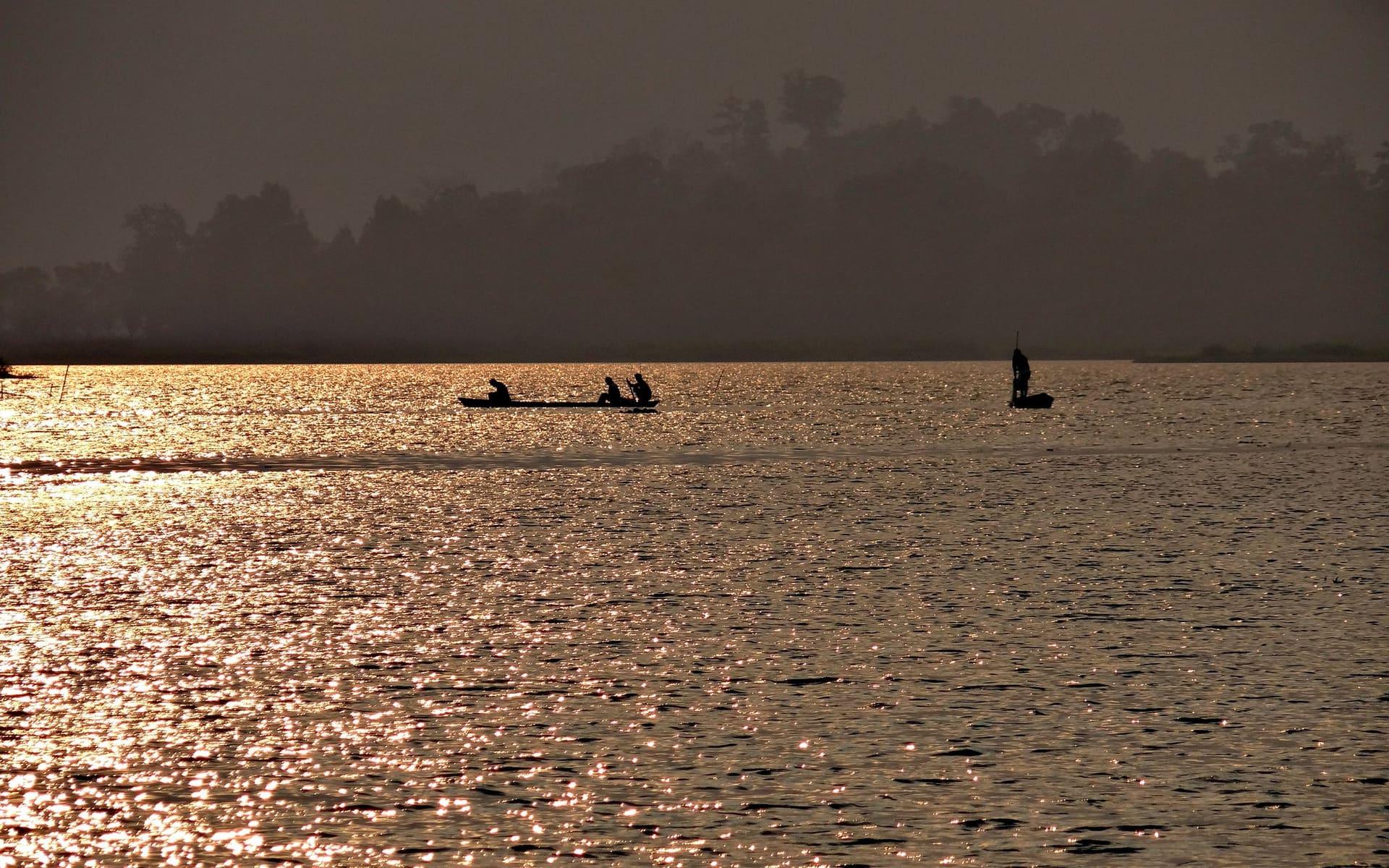 Two dugout canoes silhouetted on Chandubi lake at dawn, Assam