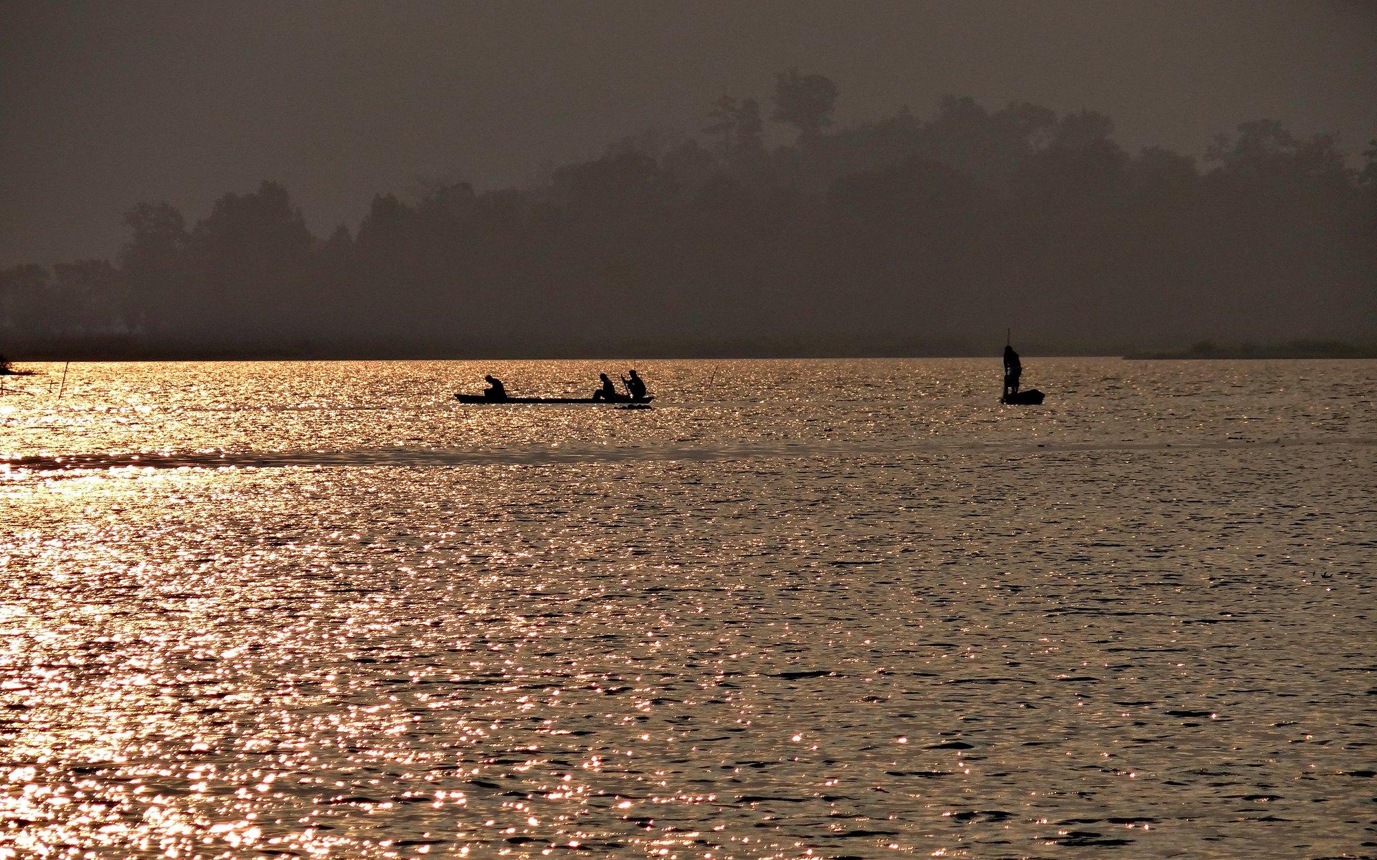 Two dugout canoes silhouetted on Chandubi lake at dawn, Assam