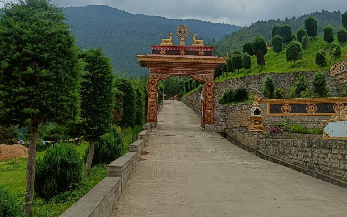 The ornate painted gate of Thupsung Dhargyeling monastery at Dirang, Arunachal Pradesh, with green hills behind