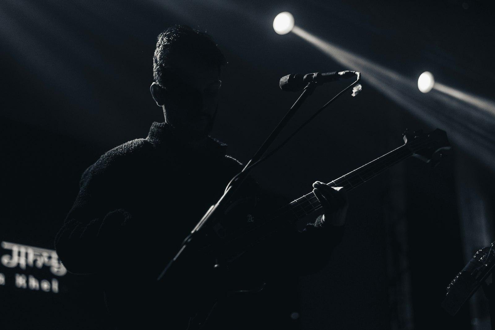 Black and white photo of a man playing guitar and singing into a microphone on stage