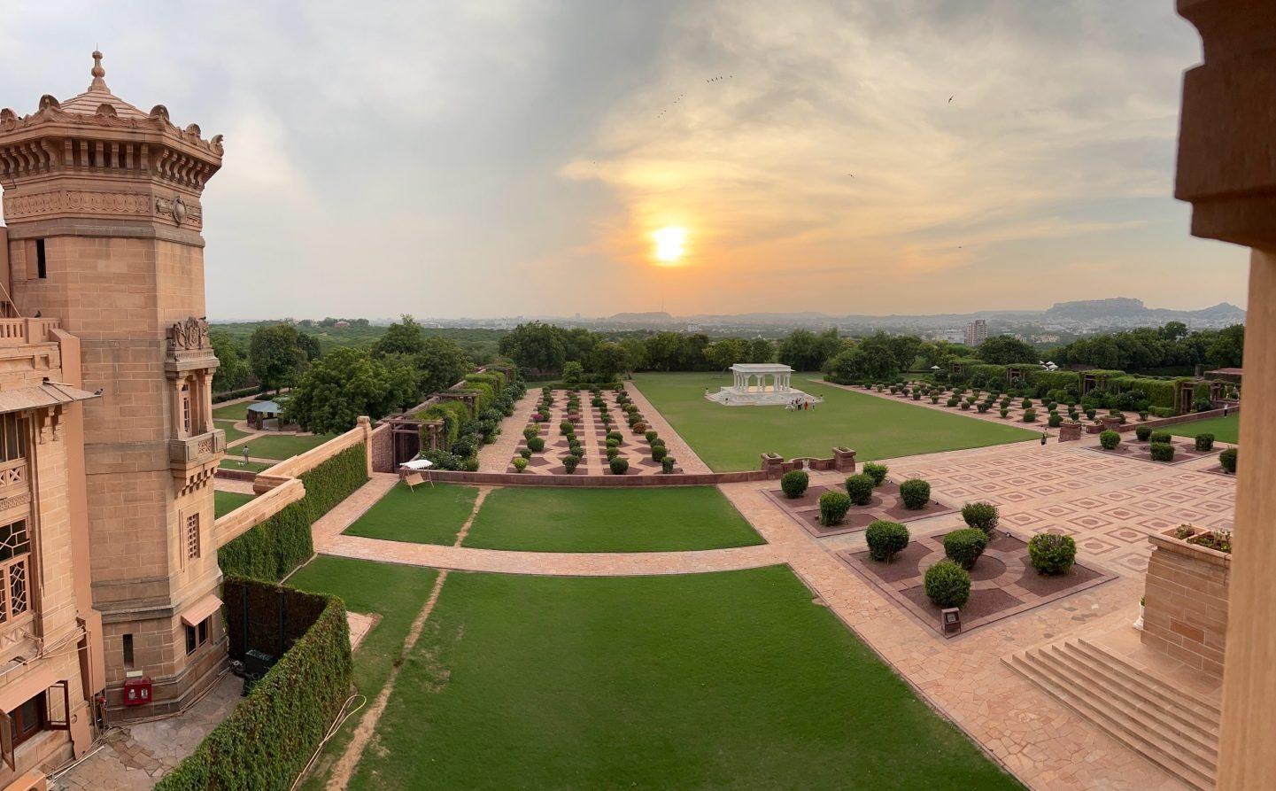 Sunset over long formal lawns and paths, seen from a sandstone balcony of the palace